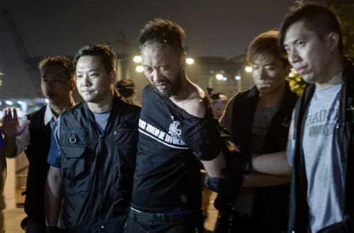 Ken Tsang (c), militant du Parti civique, est emmené par des policiers lors des manifestations pour la démocratie, le 15 octobre 2014 à Hong Kong Ken Tsang (c), militant du Parti civique, est emmené par des policiers lors des manifestations pour la démocratie, le 15 octobre 2014 à Hong Kong