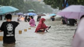 Des habitants de Zhengzhou (Chine) dans une rue de la ville envahie par les eaux, le 20 juillet 2021 