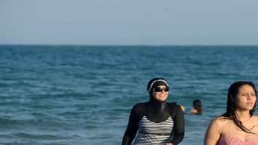 Une femme se baignant habillée, cet été sur les plages tunisiennes.