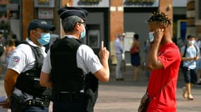 Un homme met son masque en parlant avec des policiers, sur la place du Capitole, à Toulouse, le 21 août 2020.