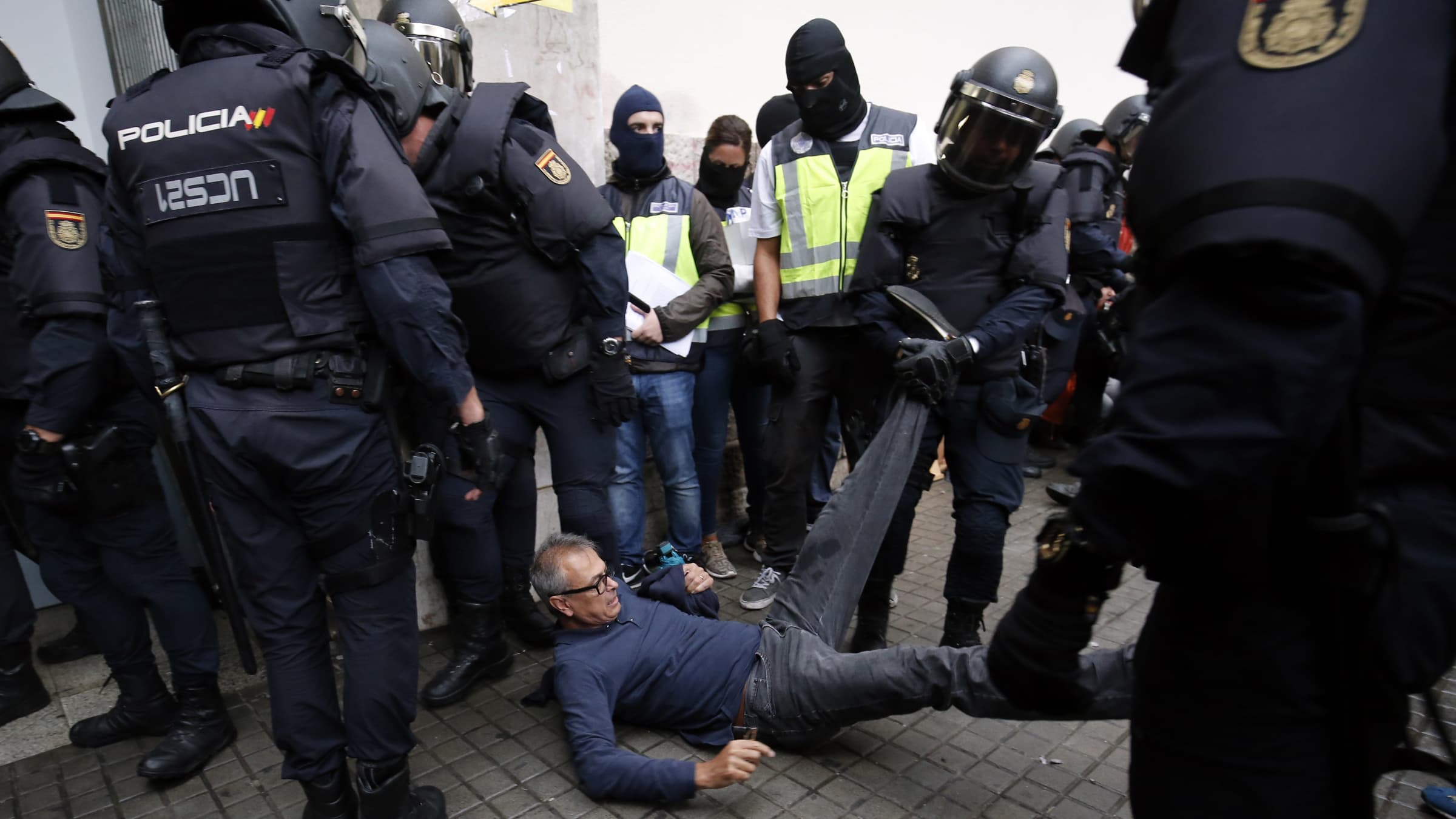 Des policiers emmènent un manifestant de force, devant un bureau de vote, à Barcelone, le 1er octobre. Des policiers emmènent un manifestant de force, devant un bureau de vote, à Barcelone, le 1er octobre.