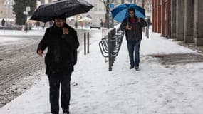 Des passants marchent dans la rue sous la neige, à Lille, le 17 janvier 2024