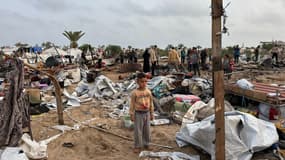 Des Palestiniens inspectent les débris sur le site de frappes israéliennes sur un camp de tentes de déplacés, dans la zone de Mawasi à l'ouest de Khan Yunis dans le sud de la bande de Gaza le 18 mai 2025.