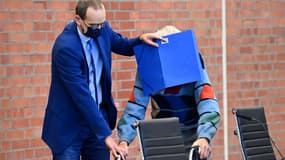 L'accusé Josef Schütz reçoit l'aide de son avocat Stefan Waterkamp pour cacher son visage derrière un dossier alors qu'il arrive pour son procès à Brandenburg an der Havel, dans le nord-est de l'Allemagne, le 7 octobre 2021.
