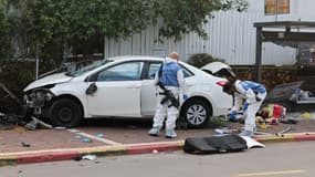 Des agents d'un équipe médico-légale de la police israélienne inspecte une voiture endommagée à la suite d'une attaque au bélier dans la ville de Ra'anana, le 15 janvier 2024.