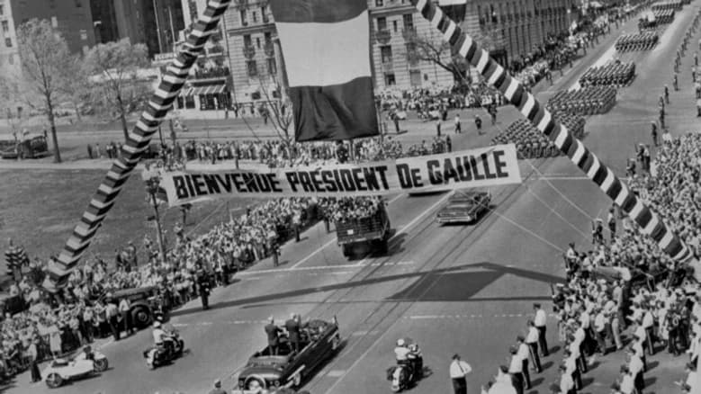 Le général de Gaulle, en voyage officiel aux Etat-Unis, traverse, le 22 avril 1960, debout dans une voiture aux côtés du président américain Dwight Eisenhower, une large avenue de Washington sous un arc de triomphe et une banderole de bienvenue au président de Gaulle.