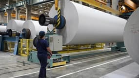 Un employé de l'usine de papier journal Norske Skog utilise une grue pour soulever un gros rouleau de papier blanc avant qu'il ne soit coupé, à Golbey, dans l'est de la France, le 24 mai 2022