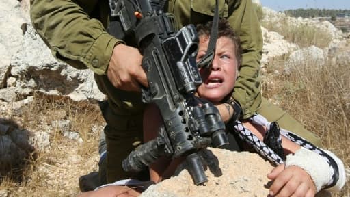 Un soldat israélien plaque un enfant palestinien sur un rocher lors d'affrontements entre les forces de sécurité israéliennes et des manifestants palestiniens, le 28 août 2015 à Nabi Saleh près de Ramallah en Cisjordanie