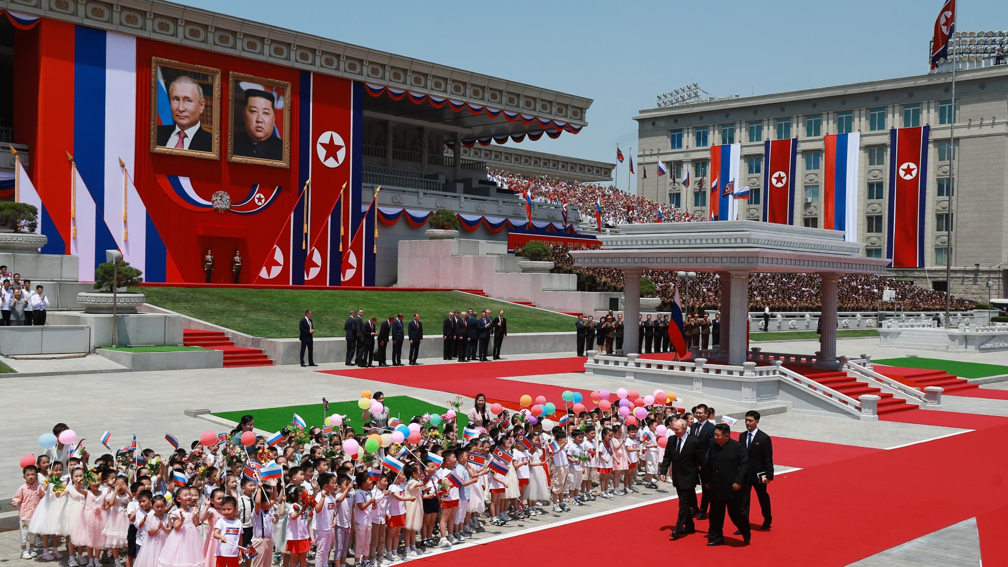 Le dirigeant nord-coréen Kim Jong Un et le président russe Vladimir Poutine passent devant des enfants lors d'une cérémonie de bienvenue sur la place Kim Il Sung à Pyongyang, le 19 juin 2024. 