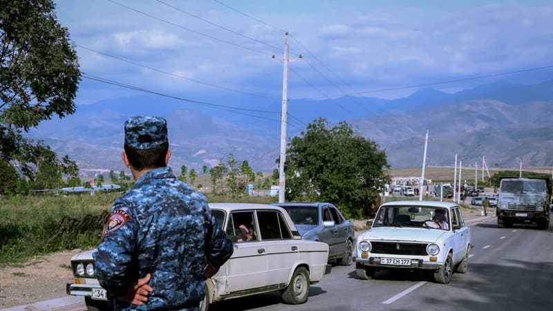 Un officier de police arménien regarde les véhicules transportant des réfugiés arriver au centre d'enregistrement, près de la ville frontalière de Kornidzor, le 24 septembre 2023.