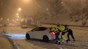 Des Espagnols poussent une voiture embourbée dans la neige à Madrid ce vendredi.