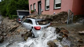 De l'eau s'écoule près d'une voiture recouverte de débris après des pluies diluviennes et des inondations à Hagen, dans l'ouest de l'Allemagne, le 15 juillet 2021