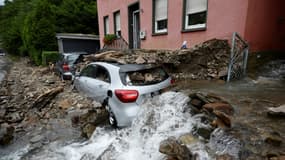 De l'eau s'écoule près d'une voiture recouverte de débris après des pluies diluviennes et des inondations à Hagen, dans l'ouest de l'Allemagne, le 15 juillet 2021