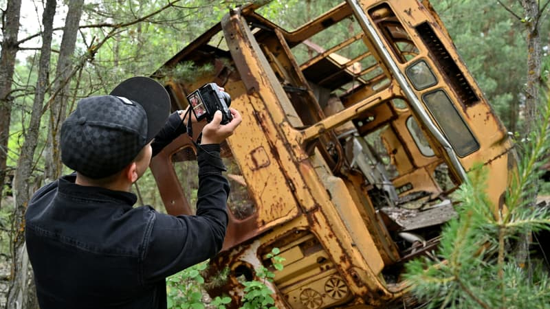 Un touriste prend une photo d'un bus abandonné à Pripyat durant un tour dans la zone d'exclusion de Tchernobyl.