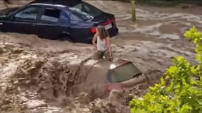 Une femme se tient sur le toit d'une voiture lors des violentes inondations qui ont frappé la ville de Saragosse, en Espagne, le 6 juillet 2023.