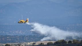 Un avion de pompiers déverse de l'eau sur les zones brûlées à la suite d'un incendie de forêt à Mentrida près de Madrid, le 18 juillet 2025.