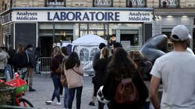 Des personnes attendent devant un laboratoire d'analyses médicales pour se faire tester au Covid-19, le 31 mars 2021 à Paris