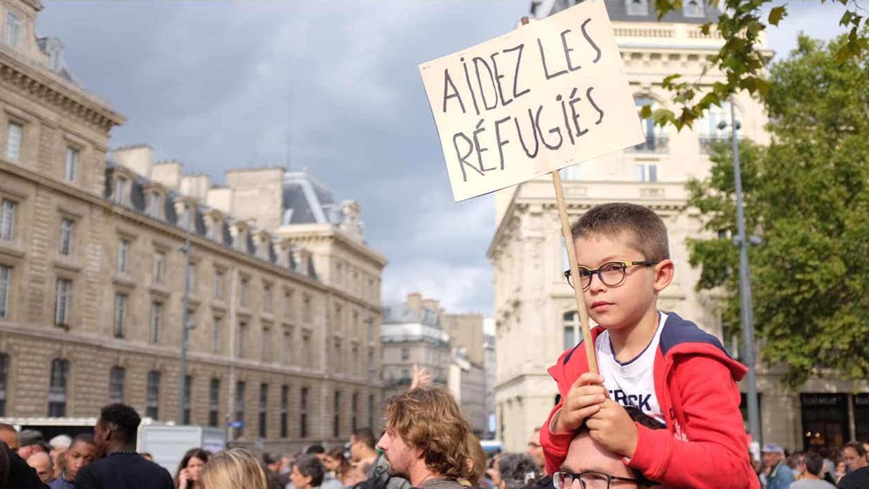 Un petit garçon porte une pancarte: "Aidez les réfugiés" Un petit garçon porte une pancarte: "Aidez les réfugiés"