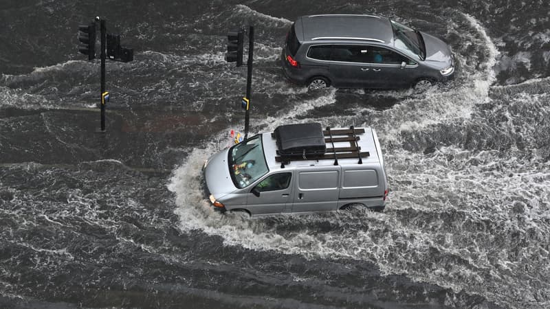 De voitures circulent tant bien que mal sur une chaussée inondée, dans le quartier Nine Elms de Londres, dimanche 25 juillet 2021