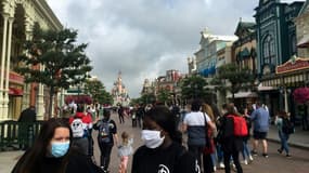 Des visiteurs portant un masque se promènent dans la rue principale de Disneyland Paris, le jour de la réouverture le 15 juillet 2020