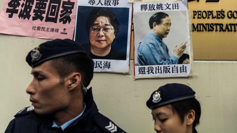 Des policiers passent devant les avis de recherche concernant Gui Minhai (à gauche), un des cinq libraires travaillant pour la maison d'édition Mighty Current, et disparus depuis 2015.