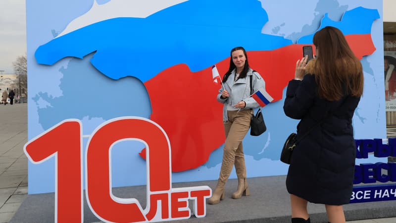 Un femme pose devant un décor célébrant les 10 ans de l'annexion russe de la péninsule ukrainienne de Crimée, à Simferopol, le 13 mars 2024