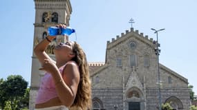 Une jeune fille se verse une bouteille d'eau sur le visage  pour se rafraîchir, en Sicile, pendant une vague de chaleur, le 16 juillet 2023.
