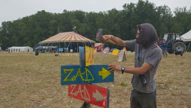 Un manifestant installe des pancartes "ZAD" (Zone à défendre) alors que des militants arrivent à un campement mis en place pour protester contre le projet d'autoroute A69 entre Toulouse et Castres, près de Puylaurens, le 7 juin 2024 dans le Tarn