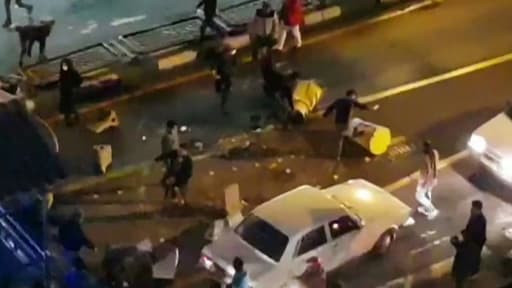 Image extraite d'une vidéo fournie par l'agence iranienne Mehr News montrant un groupe d'hommes tapant dans des plots de circulation dans une rue de Téhéran le 30 décembre 2017