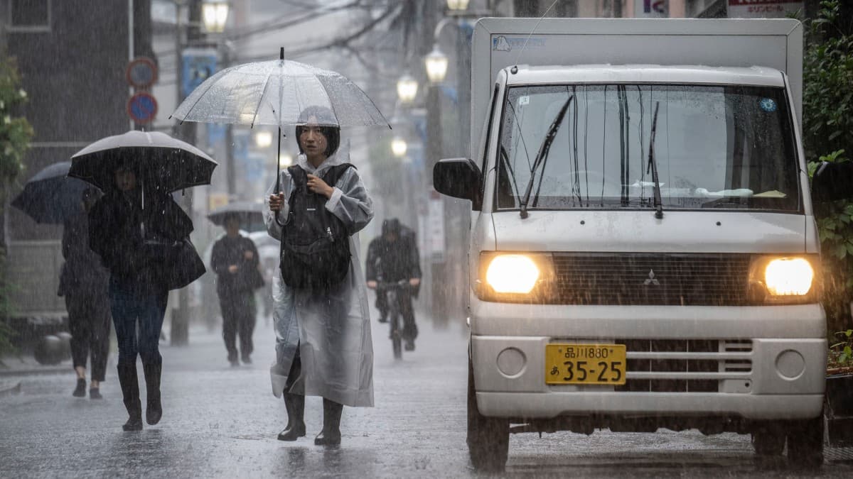 Des Japonais se déplacent sous la pluie battante à Kawasaki.