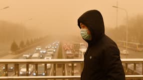 Un homme marche sur une passerelle pour piétons lors d'une tempête de sable à Pékin, en Chine, le 15 mars 2021.