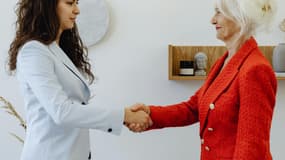 Deux femmes, une jeune et plus plus âgées, se serrent la main (photo d'illustration).