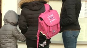 Des parents d'élèves et leurs enfants devant une école.