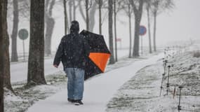 Un piéton marche avec un parapluie dans la neige dans la ville de Vimy, dans le nord de la France, le 17 janvier 2024