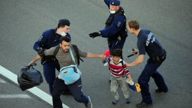 Une famille de migrants évacuée d'une autoroute par la police hongroise, à la frontière serbo-hongroise, près du village de Roszke, le 7 septembre 2015