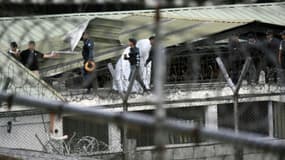 Des policiers antiémeutes marchent sur le toit d'une prison pour mineurs de San José Pinula après une opération pour libérer quatre otages, le 20 mars 2017 au Guatemala