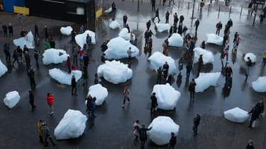 Des passants interagissent avec les blocs de glace d'une exposition intitulée "Ice Watch" créée par l'artiste dano-islandais Olafur Eliasson et le géologue groenlandais Minik Rosing, à Londres le 11 décembre 2018.