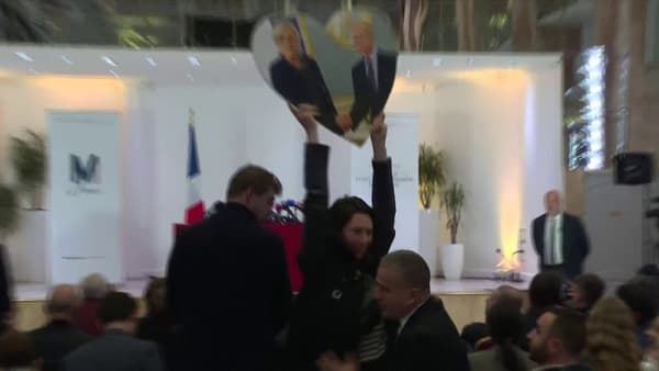 Une femme brandit une photo de Marine Le Pen et Vladimir Poutine lors d'une conférence de presse de la candidate du Rassemblement nationale