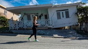 Une femme passe devant une maison endommagée par le premier séisme de magnitude 5.8 qui a touché Porto Rico lundi 6 janvier, avant le séisme de mardi 7 janvier