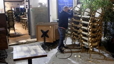 Un restaurateur empile son mobilier de terrasse.
