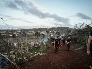 Cette photo prise et diffusée par la Sécurité civile française le 17 décembre 2024 montre des membres de la Sécurité civile marchant avec des tronçonneuses à un endroit non divulgué sur le territoire français de Mayotte dans l'océan Indien, à la suite du cyclone Chido.