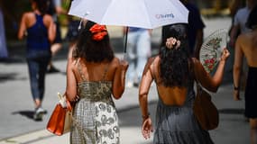 Des passantes sous un parapluie en plein soleil, durant une période de canicule à Madrid, en Espagne, le 28 juin 2025