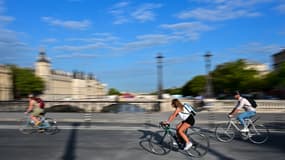 Des riverains circulent à vélo sur un pont du centre de Paris, le 22 août 2023.
