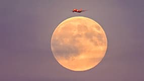 Un avion survole Leipzig en Allemagne lors de la super lune en début de soirée le 5 novembre 2025.