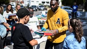 Le rappeur Mac Tyer distribuant des fournitures scolaires à des enfants d'Aubervilliers en Seine-Saint-Denis.