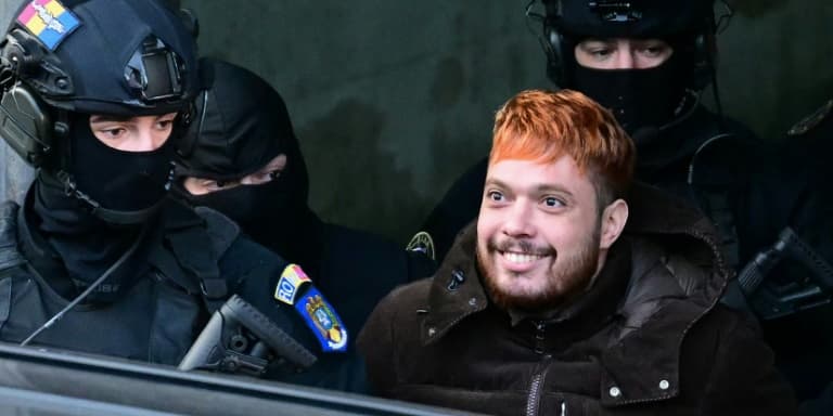 Le trafiquant de drogue français Mohamed Amra (c) escorté par des policiers hors de la Cour d'appel de Bucarest, le 23 février 2025, au lendemain de son arrestation en Roumanie