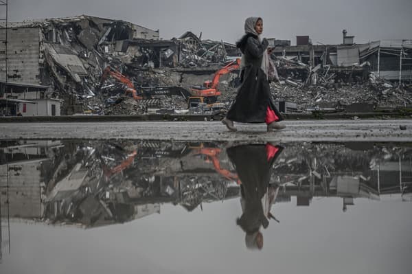 Une femme marche devant les décombres d'habitations, un an après les séismes en Turquie et en Syrie, le 12 janvier 2024 à Antakya, en Turquie