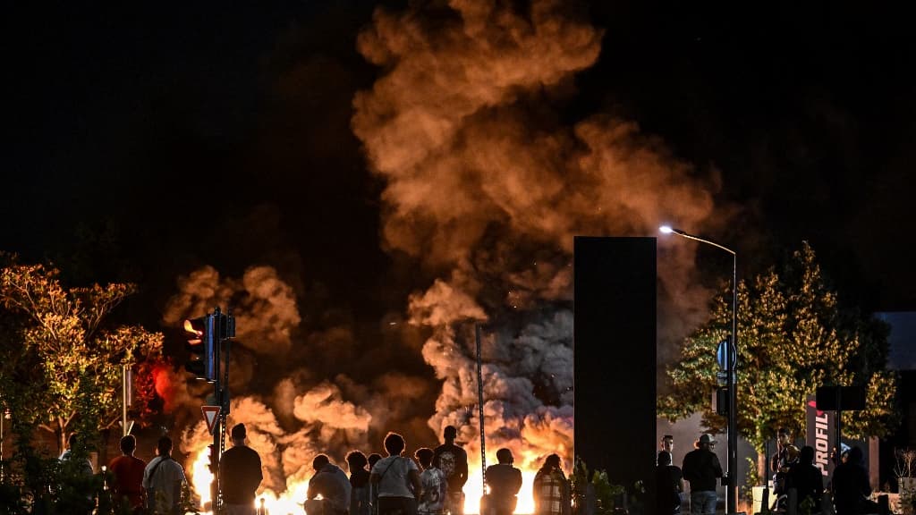Un groupe de personnes regardent des pneus brûlés à Bordeaux lors d'une nuit d'émeutes le 29 juin 2023