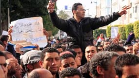 Un homme, à Tunis, avec un sèche-cheveu en référence à l'ex-première dame de Tunisie Leïla Trabilsi lors d'une manifestation appelant à former un gouvernement sans membres ayant officié sous le régime de Zine Ben Ali. La télévision locale a en outre annon