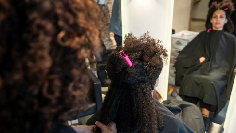 Rola Amer, coiffeuse au salon "Curly Studio" pour cheveux crépus et bouclés, coupe les cheveux d'une cliente, le 2 mars 2022 à Paris